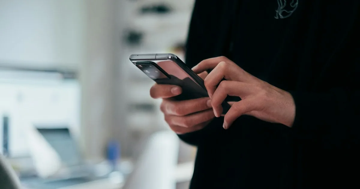 Persona consultando su smartphone en un espacio de trabajo