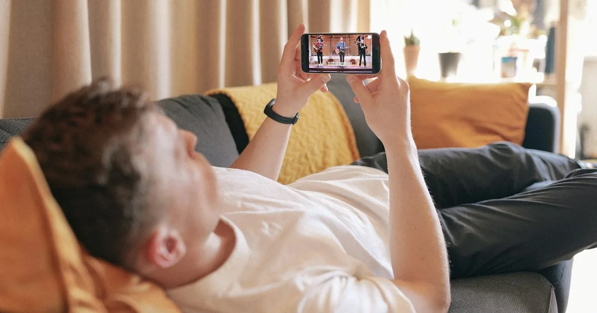 Hombre tumbado en el sofá viendo un vídeo en su móvil