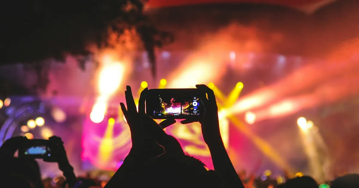Público grabando un concierto con el móvil entre luces de escenario