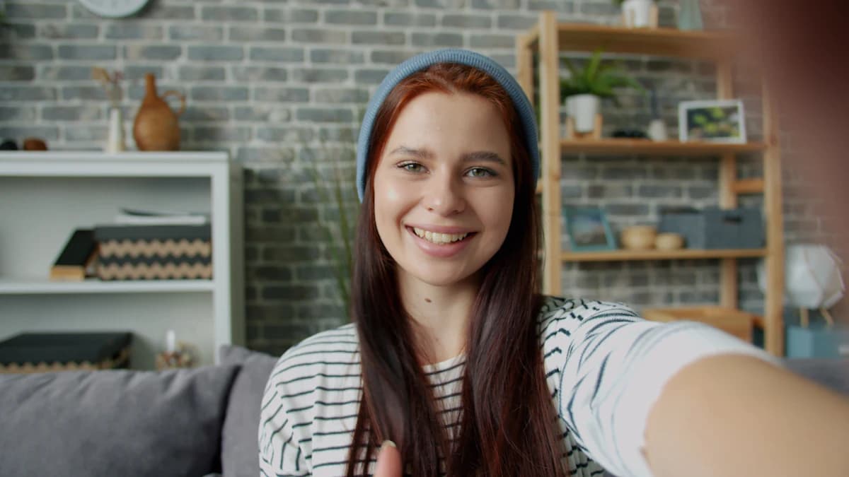Chica con gorro hablando a la cámara del móvil en su salón